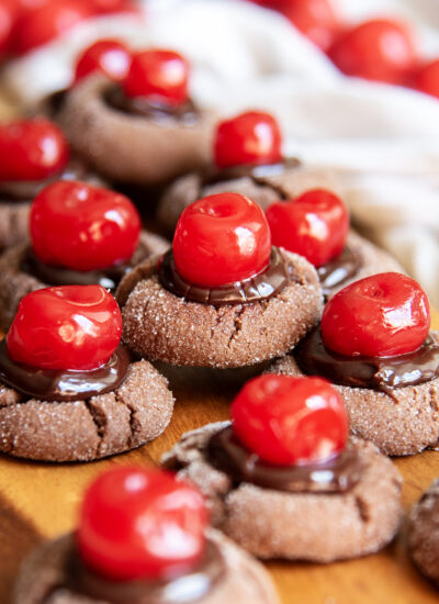 A pile of chocolate cherry cookies topped with chocolate ganache and red maraschino cherries.
