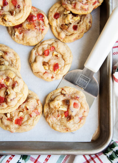 A fruitcake cookie on a metal spatula on a cookie sheet.