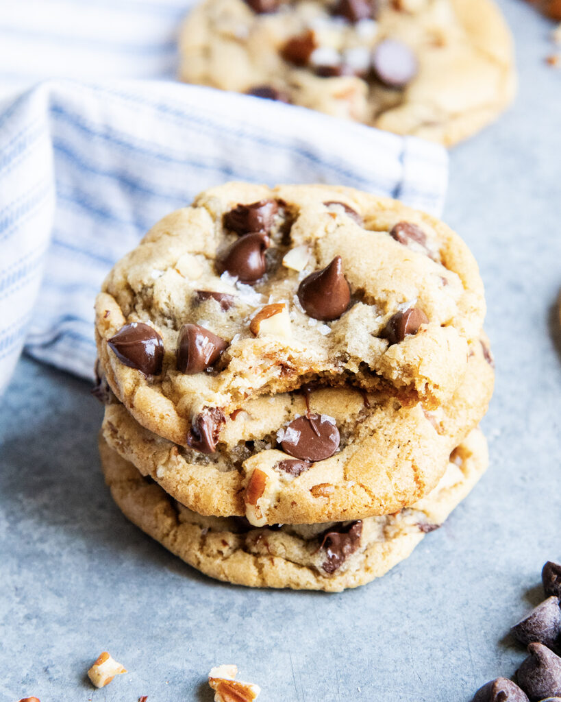 A stack of three maple chocolate chip cookies with a bite out of the top cookie.