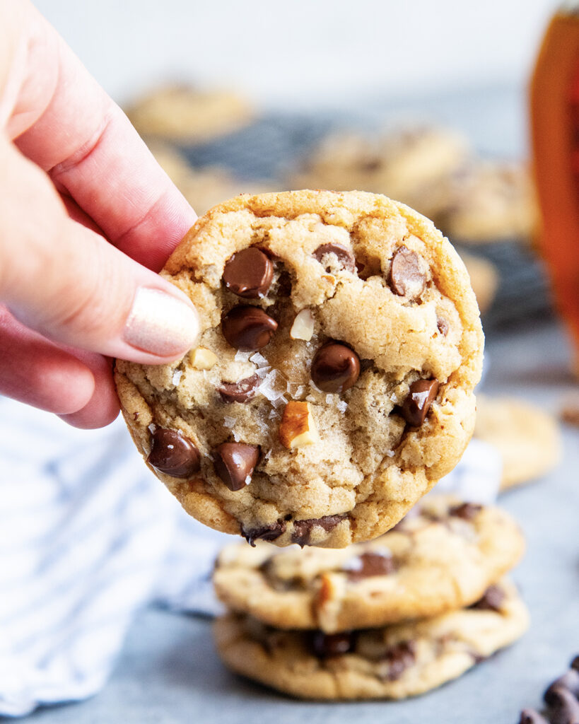 A hand holding a maple pecan chocolate chip cookie.