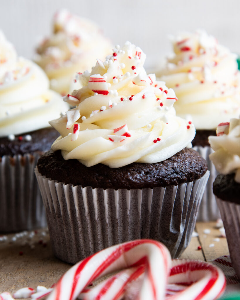 A peppermint frosted cupcake topped with candy cane pieces. 