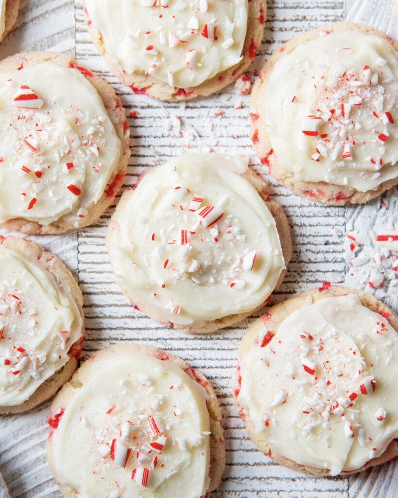 An above view of peppermint Sugar cookies topped with icing and candy cane pieces.