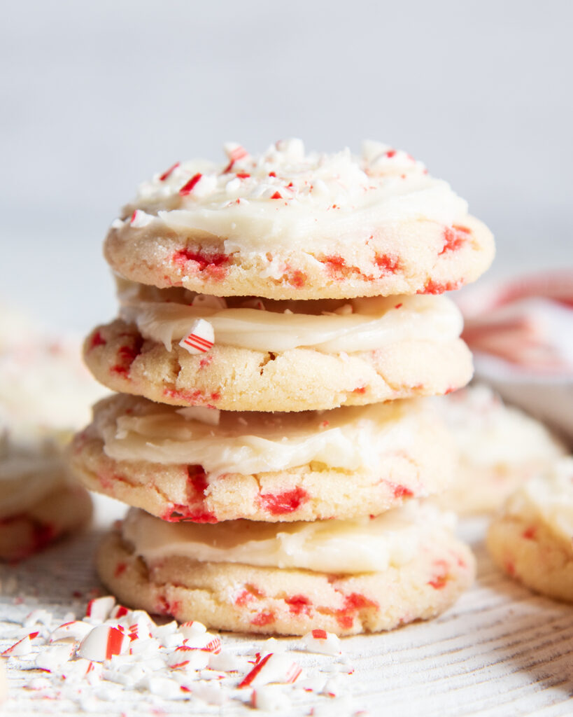 A stack of 4 Candy Cane Cookies with frosting, and candy cane pieces. 