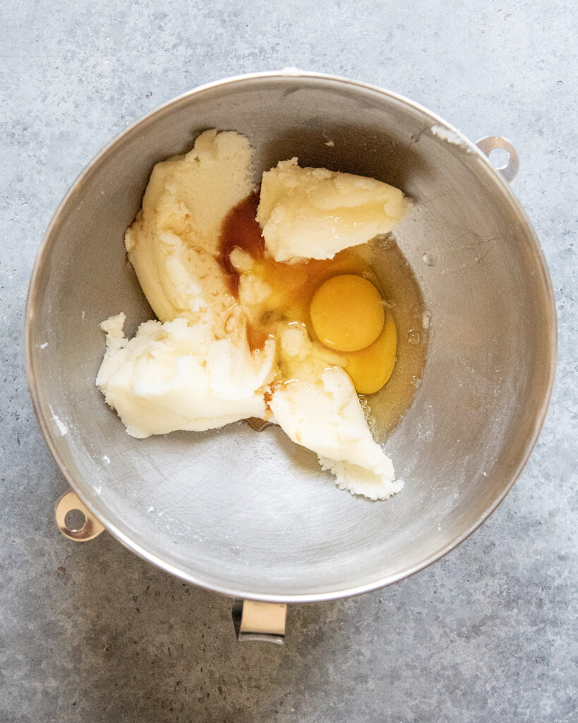 A bowl of creamed butter topped with eggs and vanilla extract.