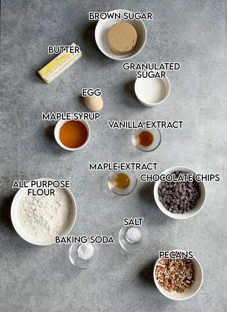 An above photo of the ingredients needed to make maple chocolate chip cookies, in small bowls. 