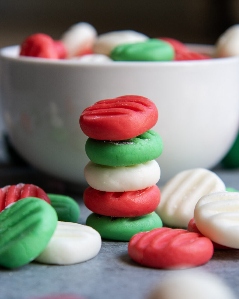 A stack of small coin sized cream cheese mints, in Christmas colors.