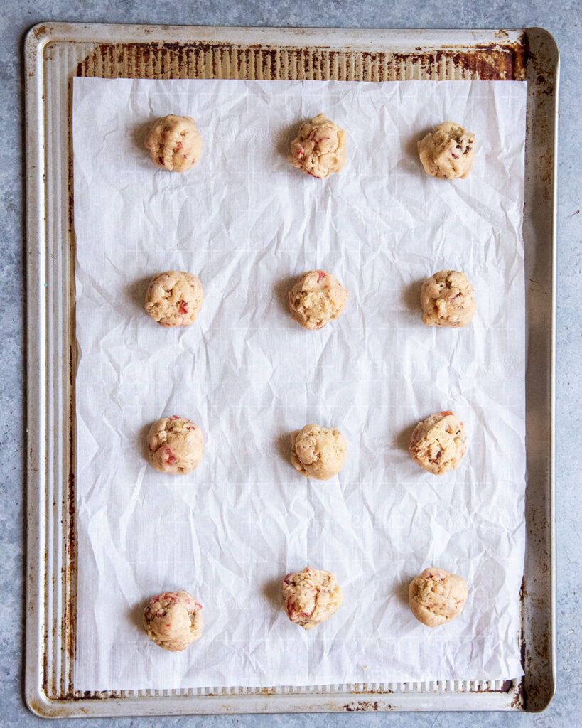 Scoops of cookie dough balls on a metal cookie sheet.