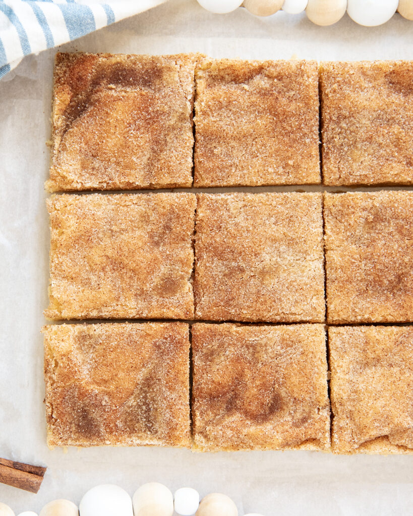 Rows of snickerdoodle cookie bars on a piece of parchment paper.