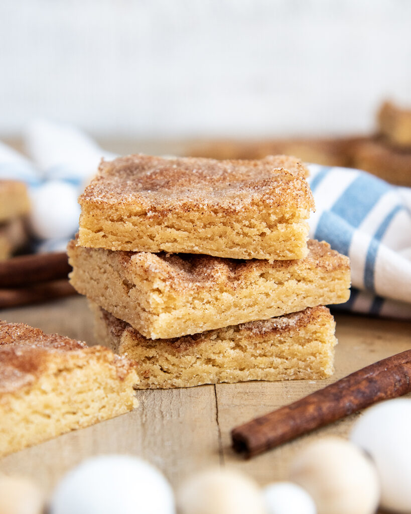 A stack of three snickerdoodle cookie bars, surrounded by a white and blue cloth.