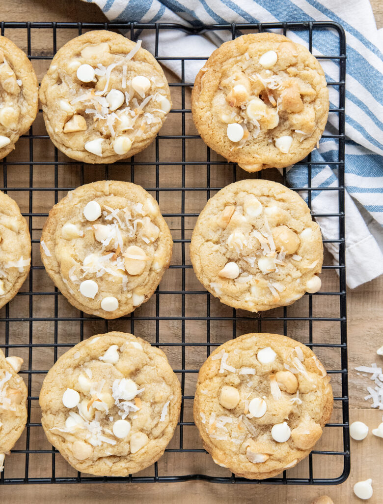 Rows of white chocolate macadamia nut cookies on a wire cooling rack.