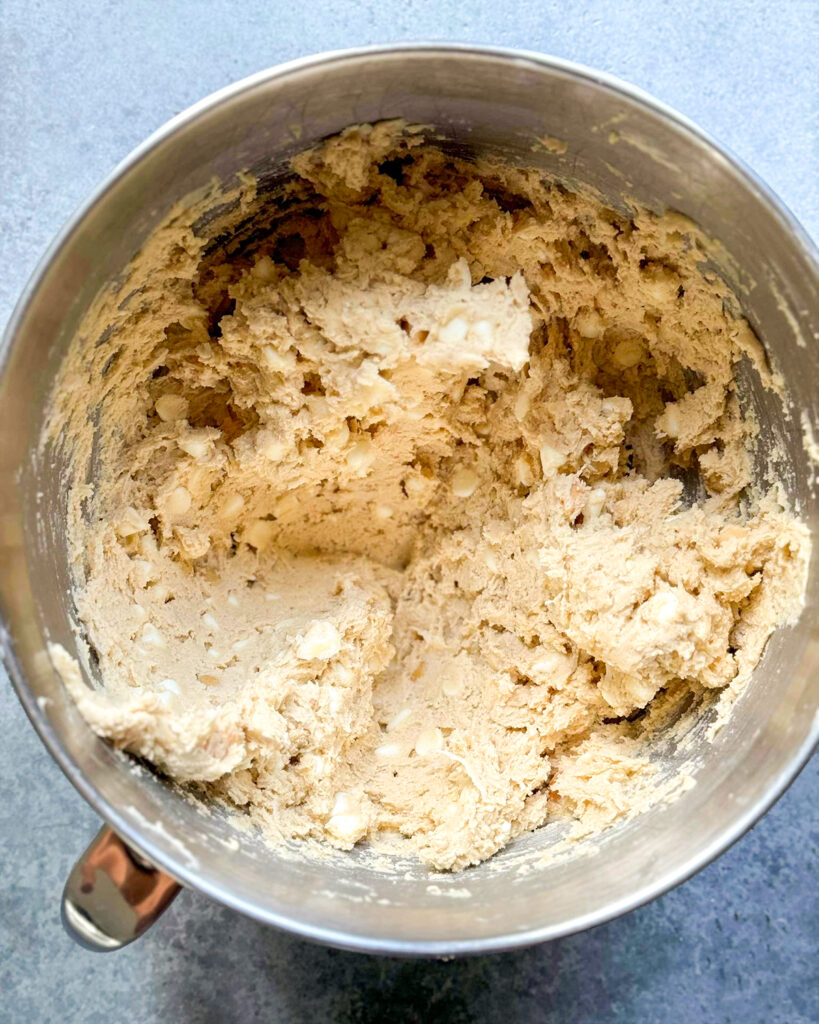 White chocolate macadamia nut cookie dough in a metal mixing bowl.