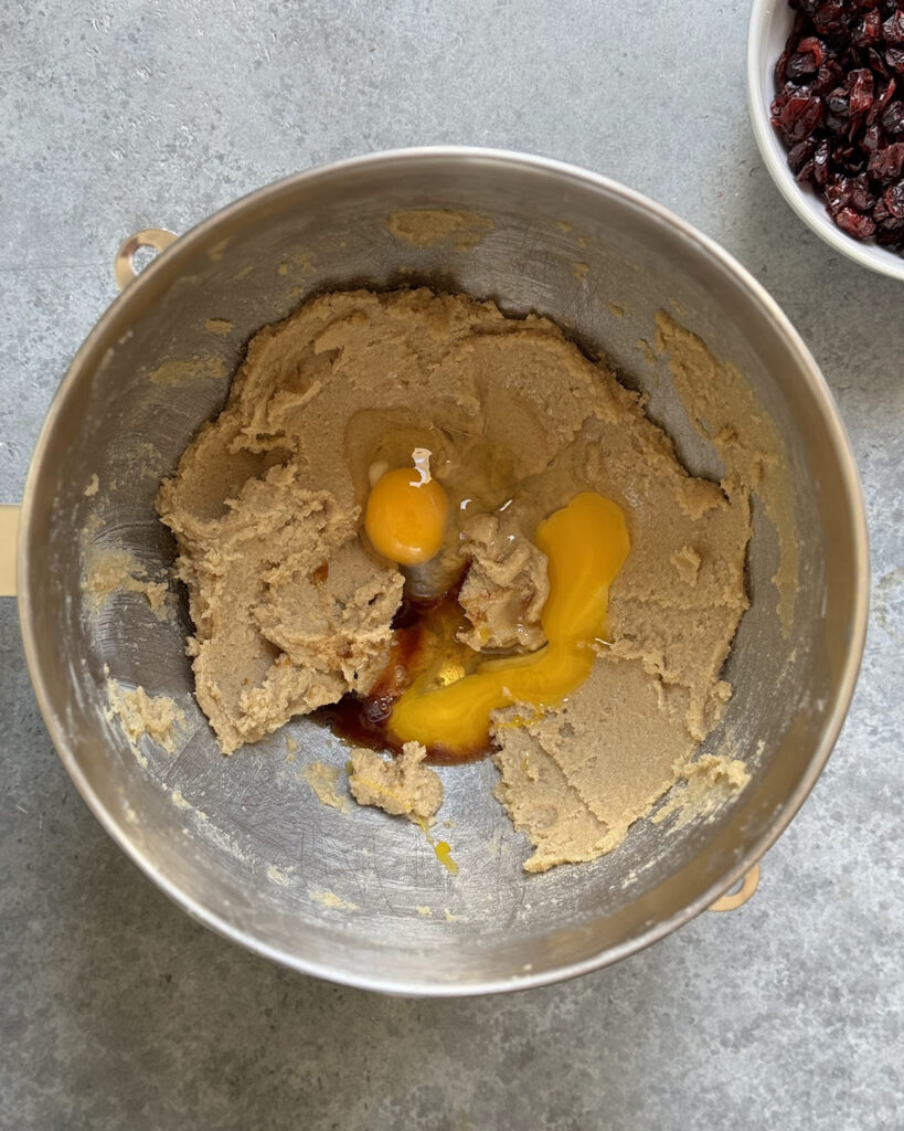 A bowl of brown sugar and butter creamed, with eggs and vanilla extract on top. 