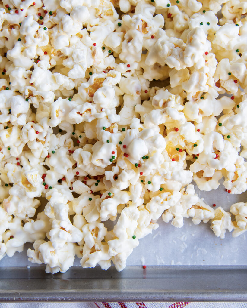 A close up of white chocolate coated popcorn on a baking pan. 