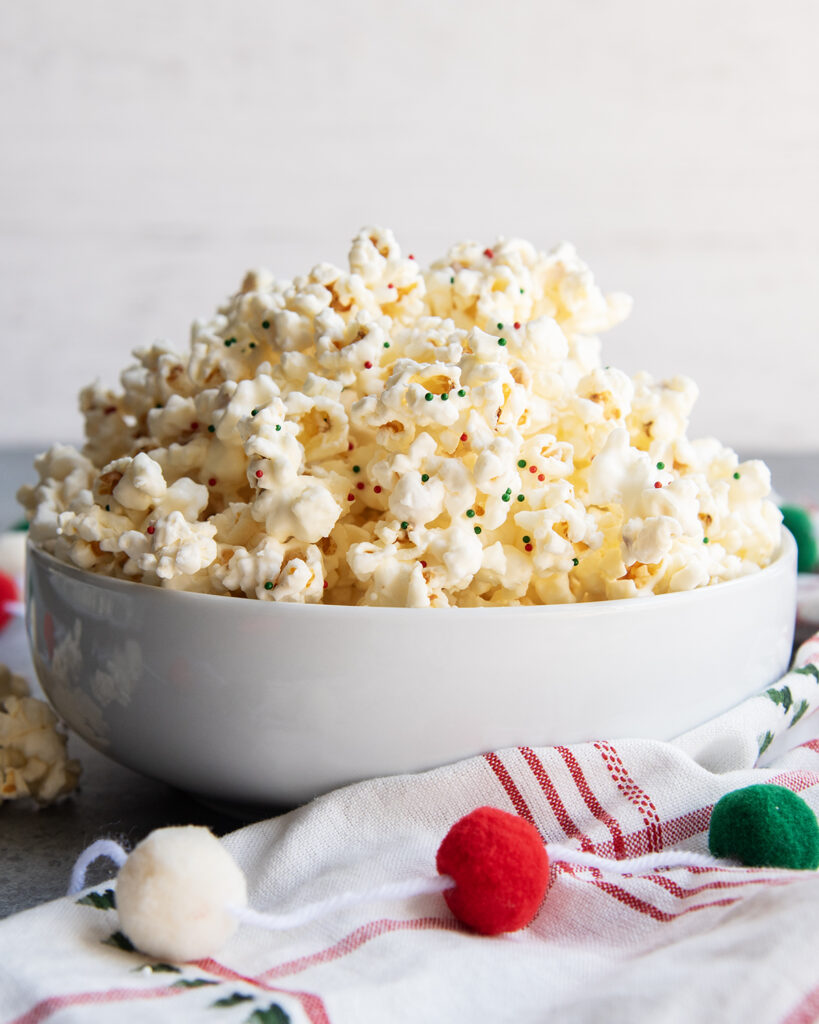 A white bowl piled with white chocolate popcorn.