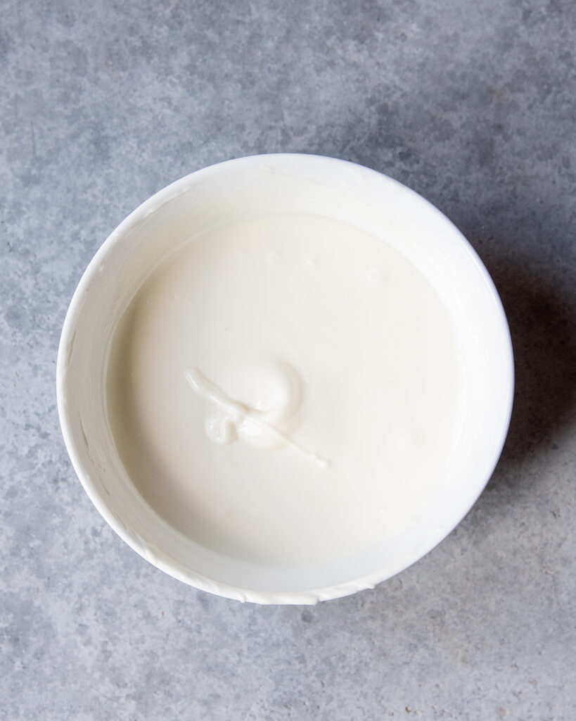 An above view of a bowl of melted white chocolate .