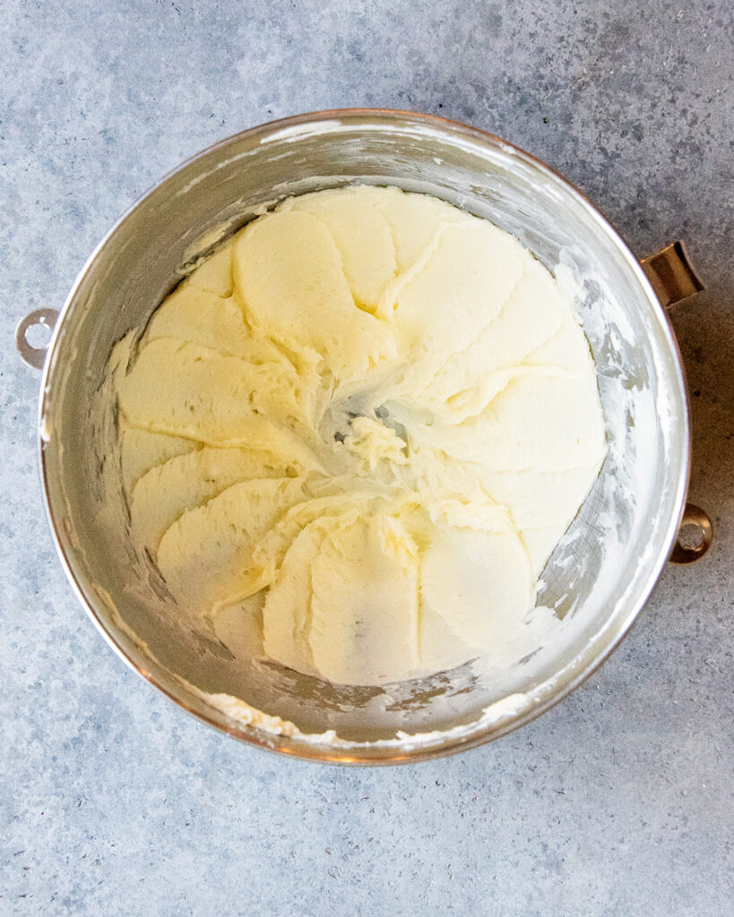 A metal mixing bowl full of beaten butter.  