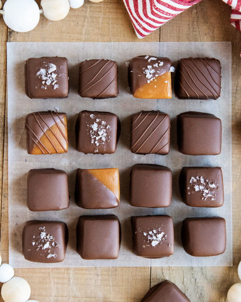 Rows of chocolate coated caramels on a piece of parchment paper.