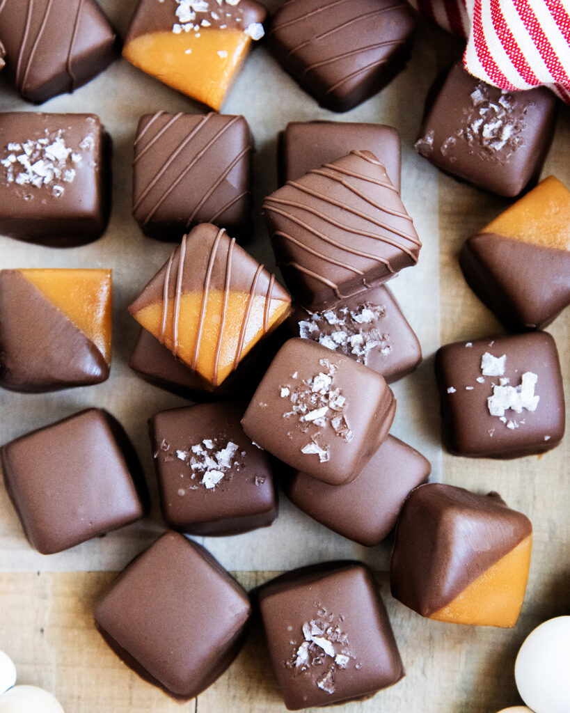 An above view of a pile of chocolate covered caramels, some have sea salt on top.