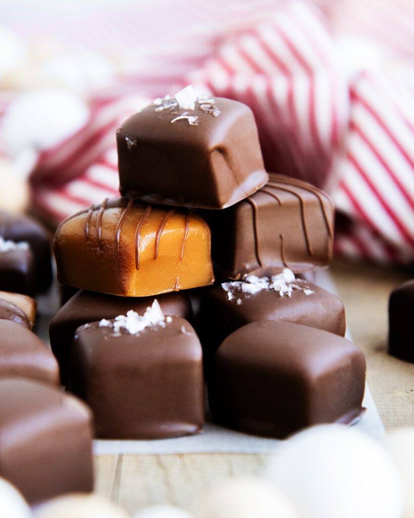 A pile of chocolate coated caramels, some are topped with sea salt.