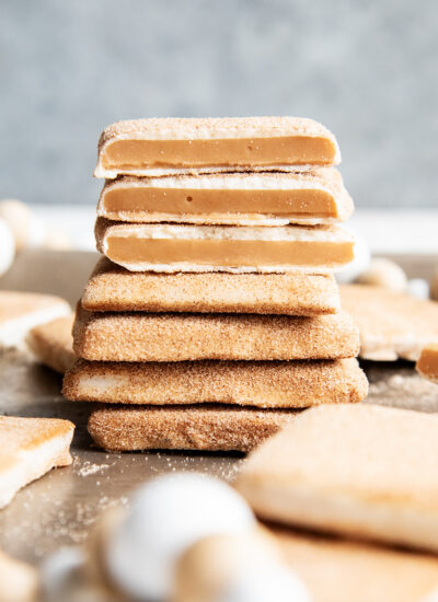 A stack of cinnamon sugar and white chocolate churro toffee. The top three pieces are broken in half showing the middle of the toffee.