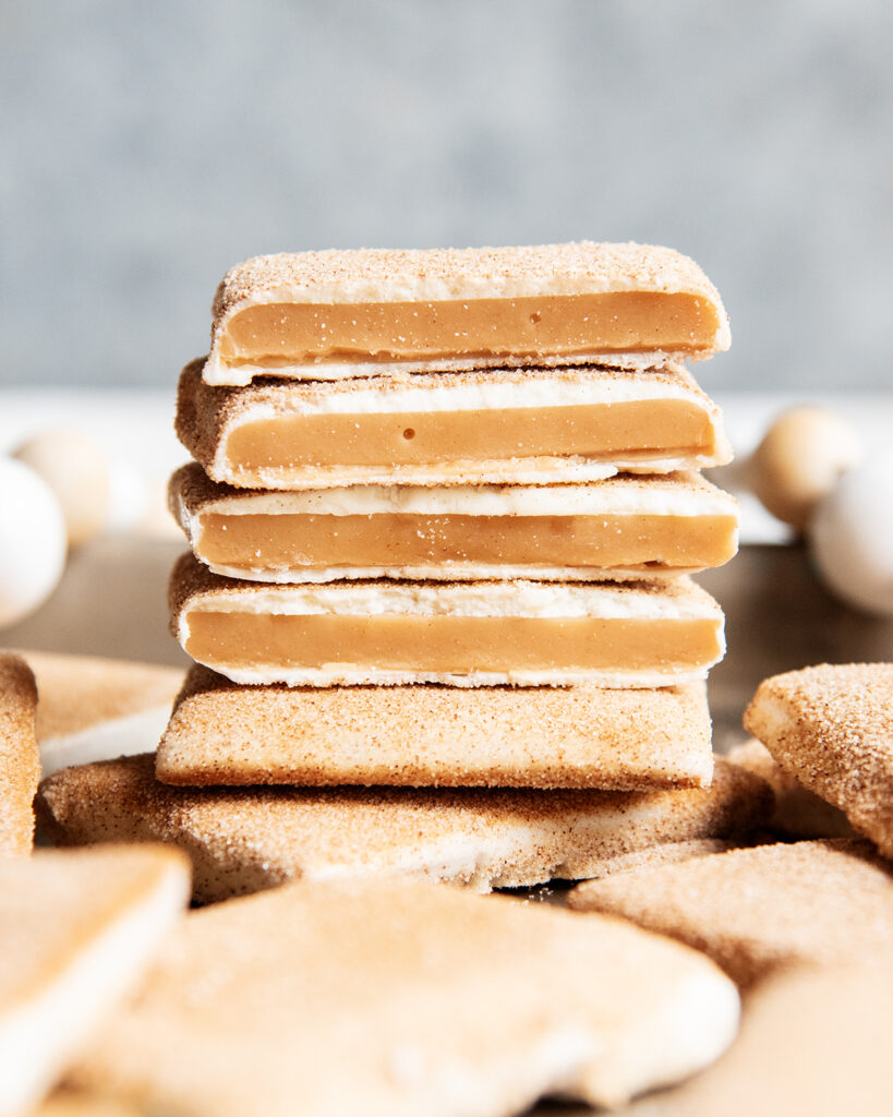 A stack of 4 pieces of white chocolate coated toffee showing the toffee in the middle of the white chocolate.