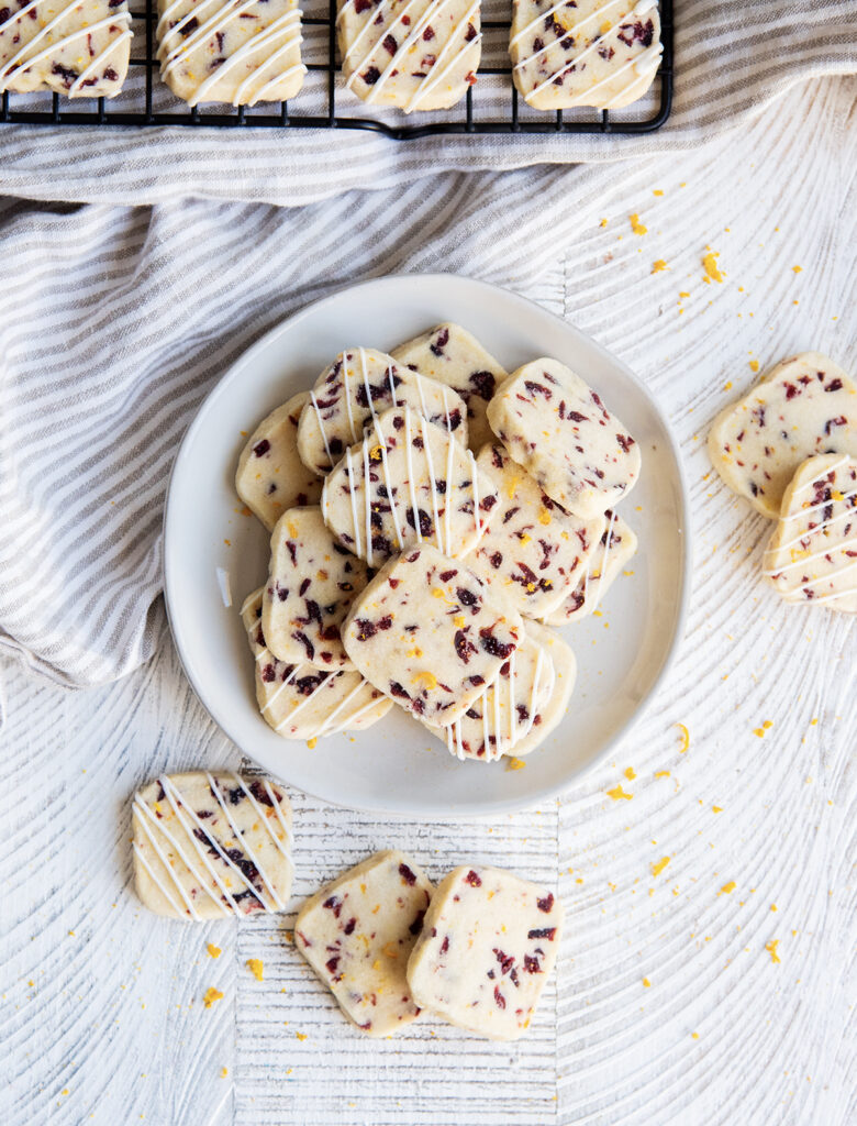 An above view of a white plate topped with square cranberry orange shortbread cookies.