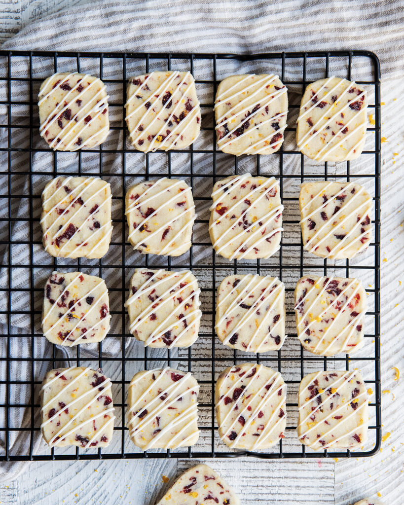 An above view of rows of square shortbread cookies on a wire cooling rack.