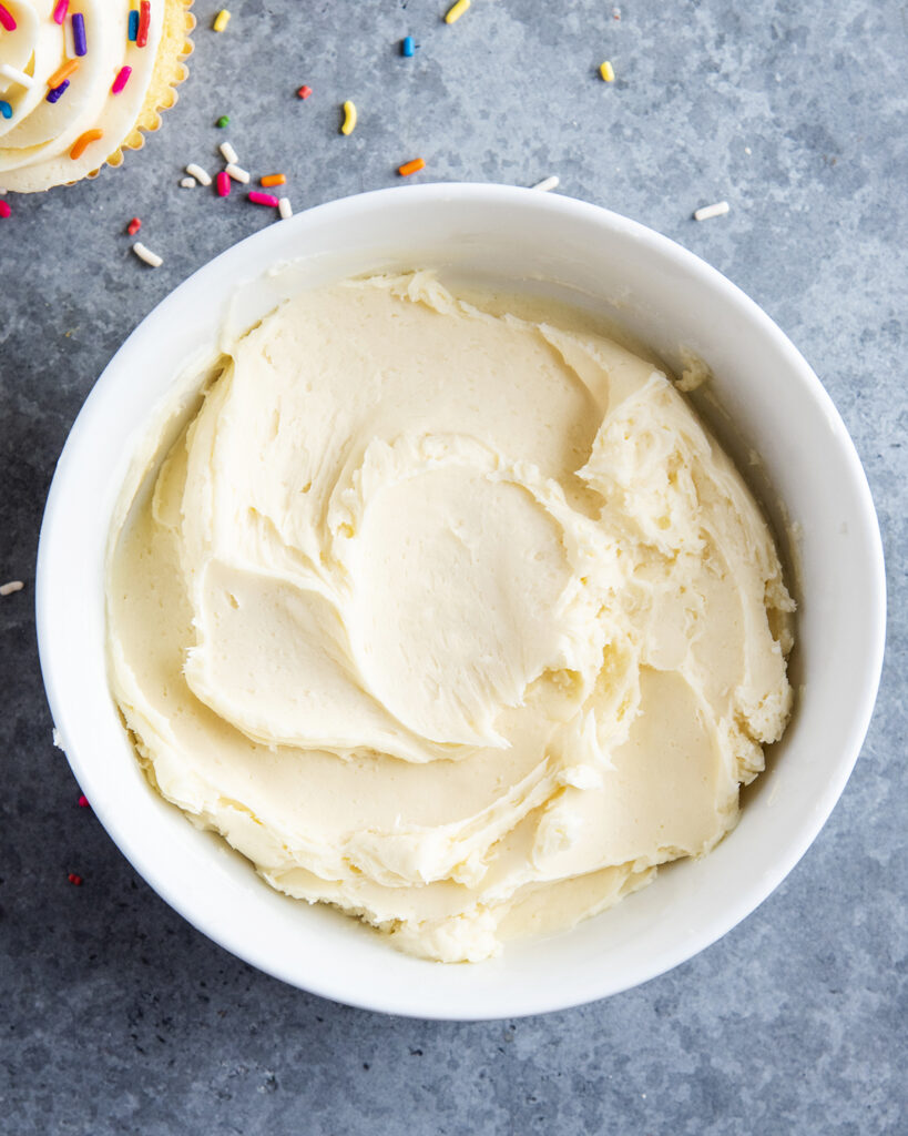 A white bowl full of white buttercream frosting. 