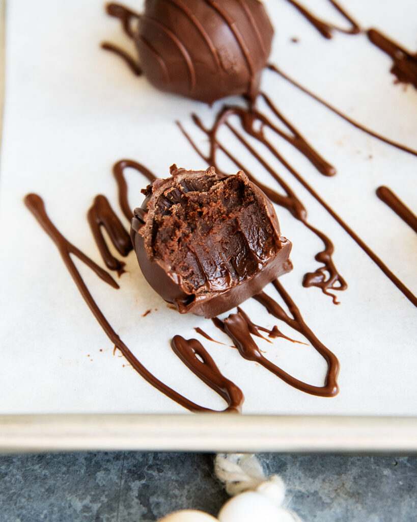 A chocolate mint truffle with a bite out of it, showing the soft truffle center. 