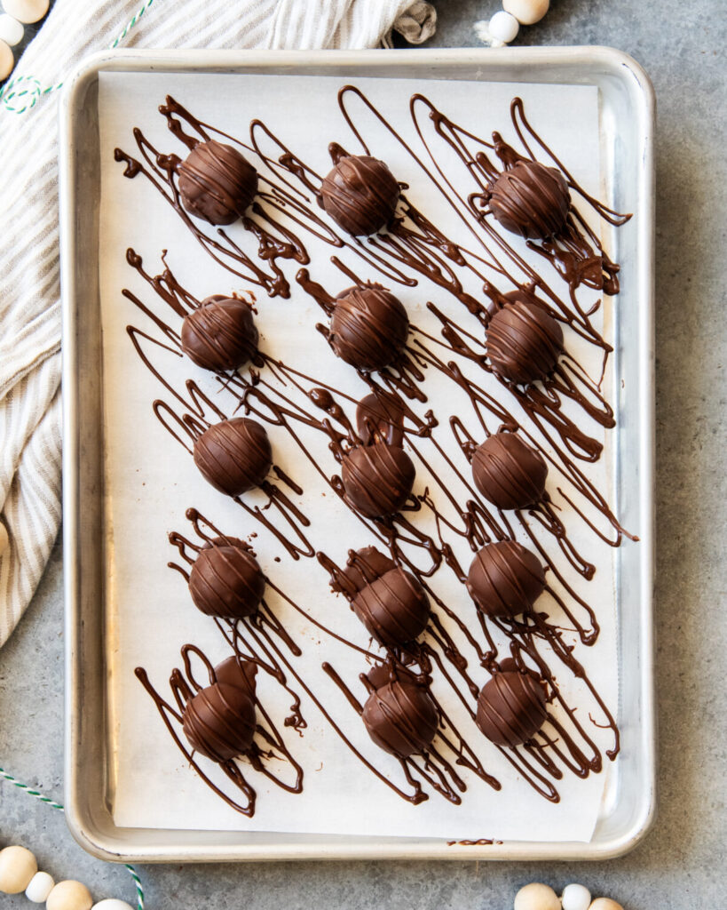 An above view of chocolate mint truffles drizzled with extra chocolate on a cookie sheet.