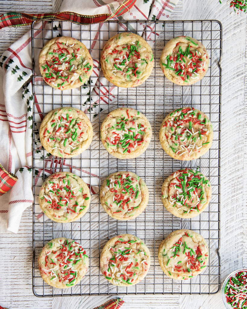 An above view of Christmas sprinkle sugar cookies on a cooling rack.