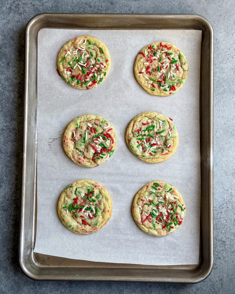 Six Christmas Sprinkle Cookies on a cookie tray.