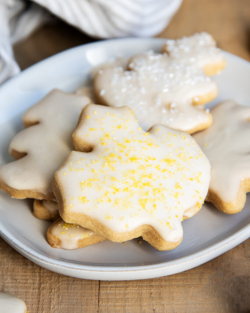 A plate of leaf shaped sugar cookies topped with icing and sprinkles. 