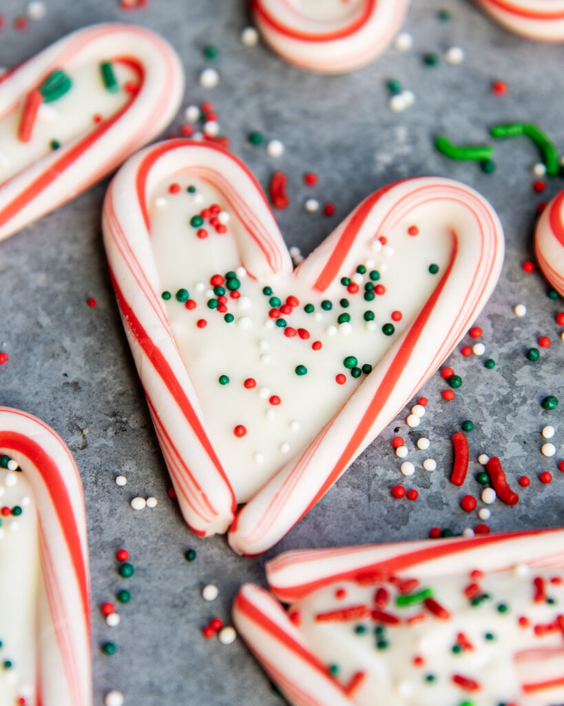 A candy cane heart filled with white chocolate and topped with holiday sprinkles.