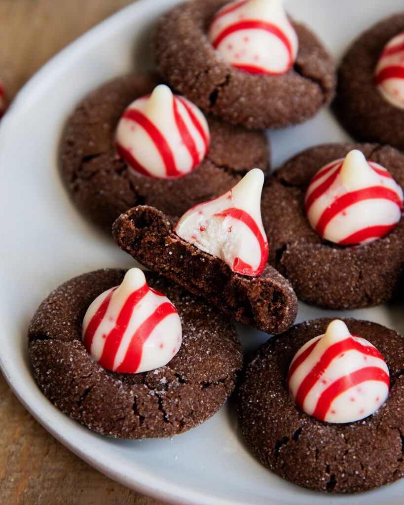 A plate of Chocolate Peppermint Kiss Cookies, and one has a bite out of it.