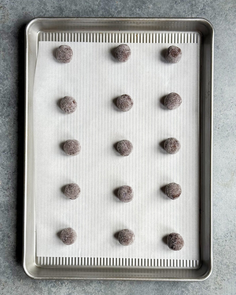 Balls of chocolate cookie dough on a baking tray. 