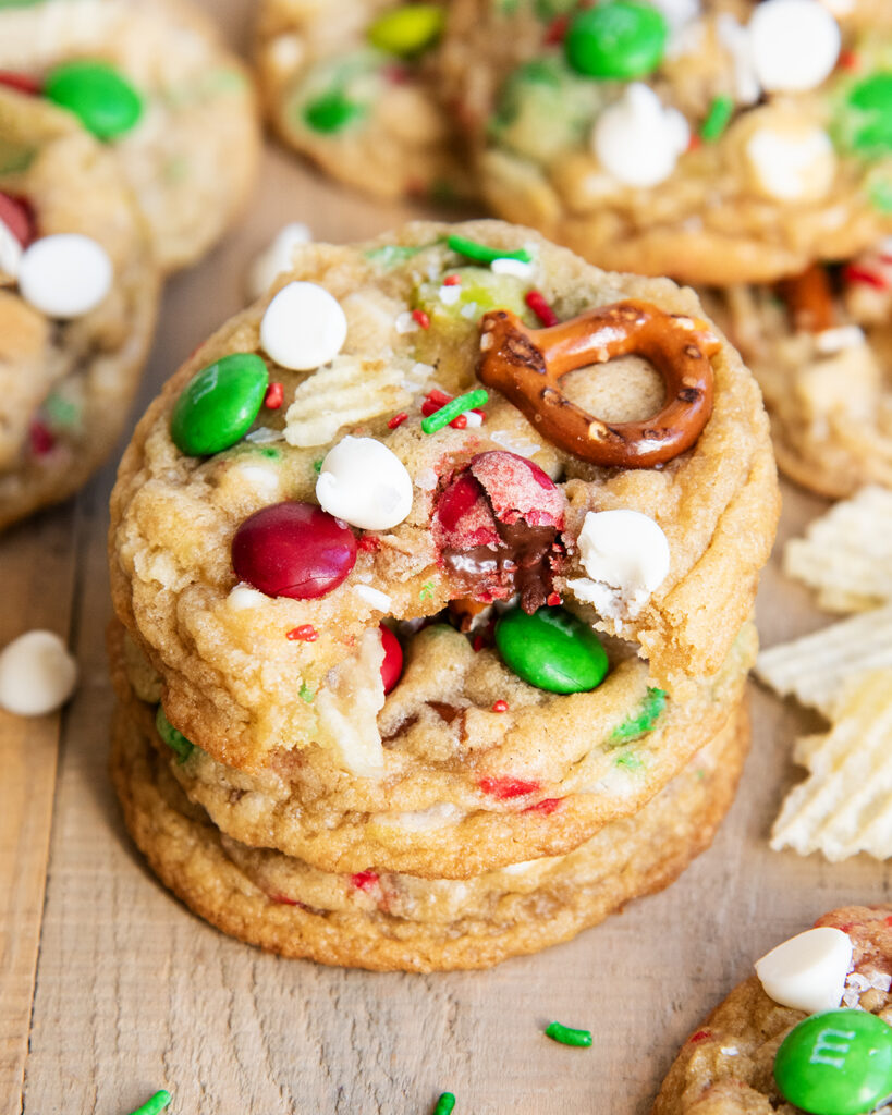 A stack of Christmas Kitchen Sink Cookies, and the top cookie has a bite out of it.