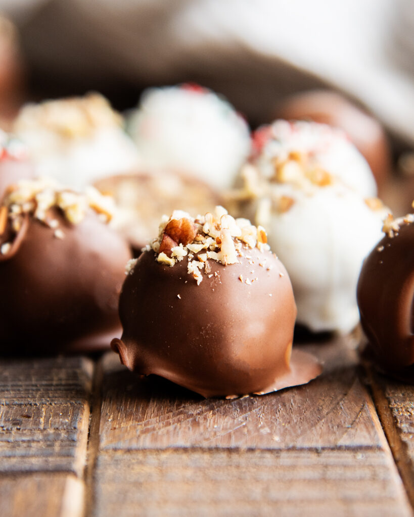 A chocolate coated pecan pie ball topped with finely chopped pecans.