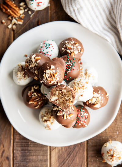 A pile of pecan pie balls on a plate, one is cut in half showing the pecan pie filling.