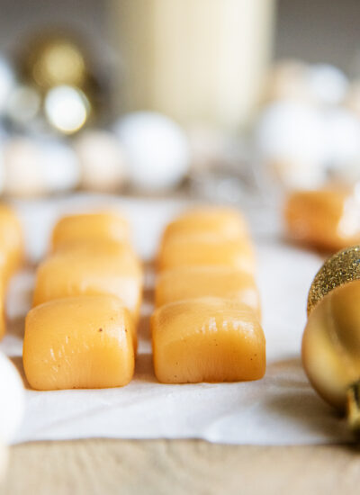 Rows of eggnog caramels next to ornaments on a table.