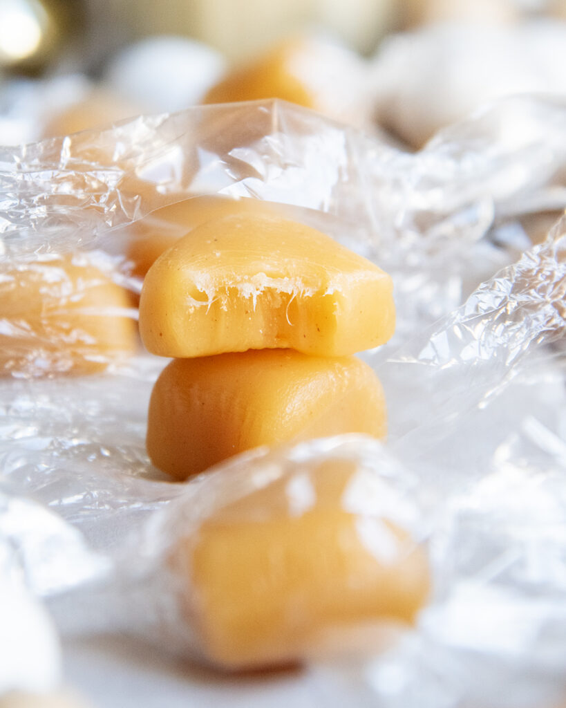 A stack of two caramels, the top caramel has a bite out of it.