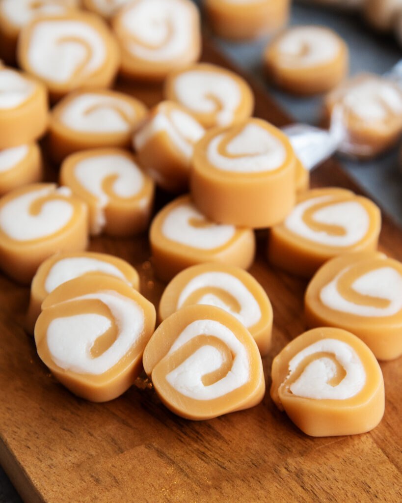 A pile of cream filled caramels on a wooden board. 