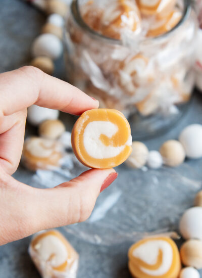 A hand holding a Vanilla Caramel Cream with vanilla swirl in the middle.