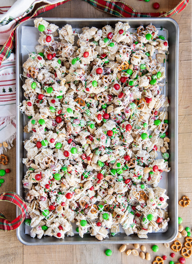 An above view of a pan of white chocolate chex mix topped with red and green m&ms.