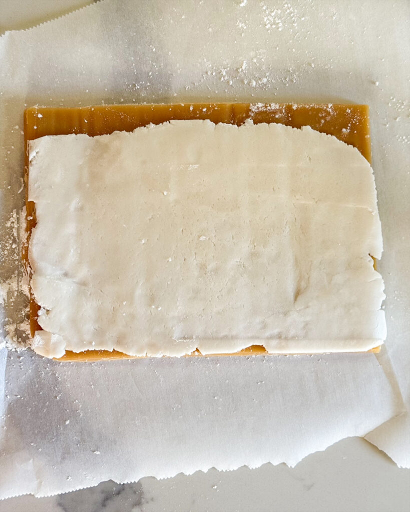 A slab of caramel topped with vanilla cream.