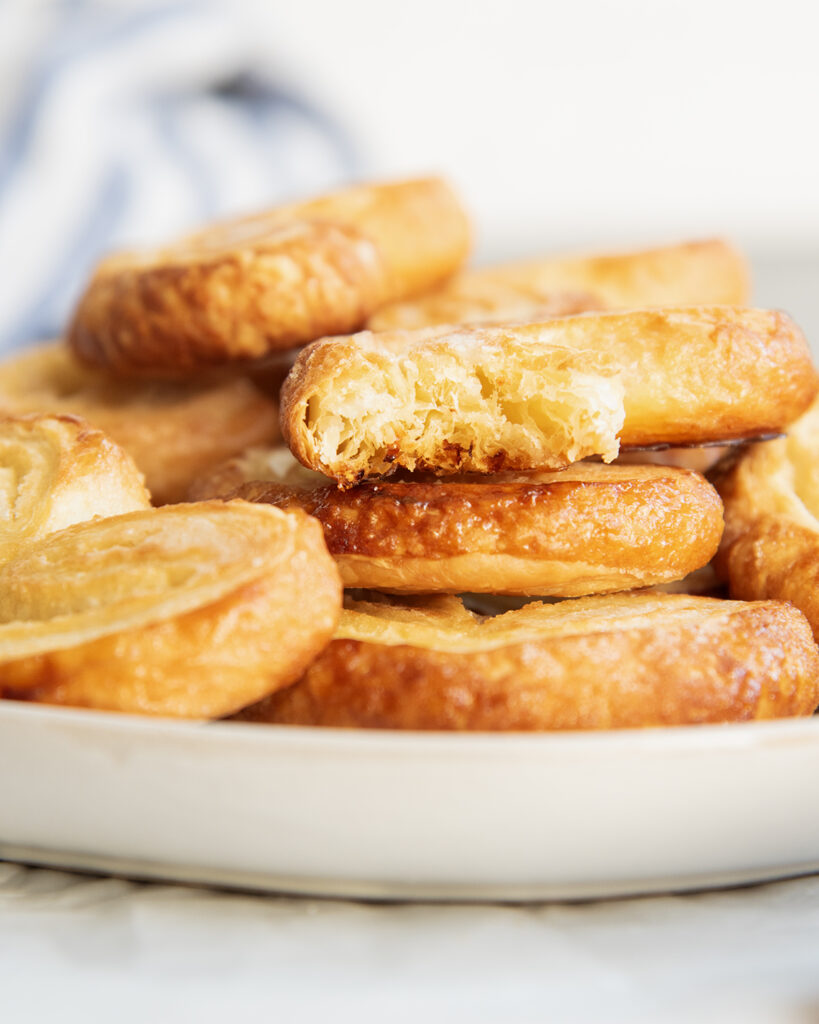 A plate of puff pastry palmiers, and one has a bite out of it.