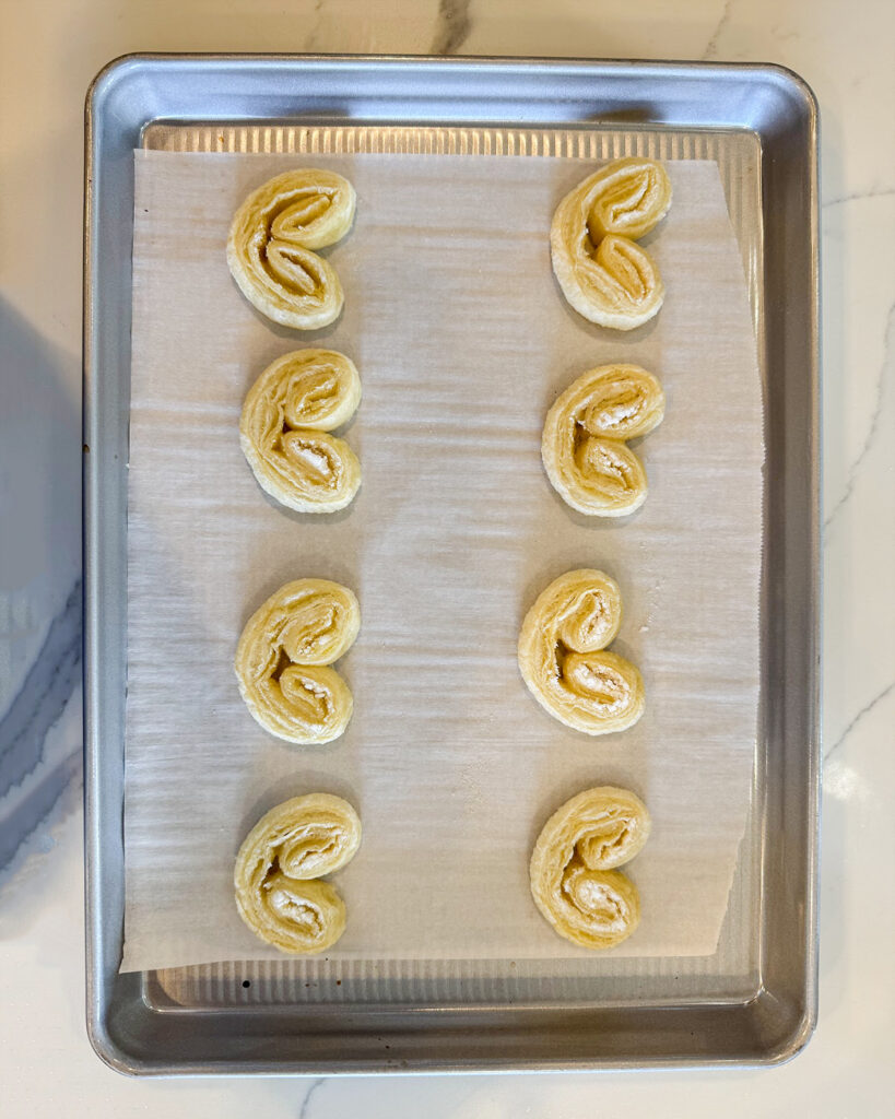 Puff Pastry Palmiers half baked on a cookie sheet.