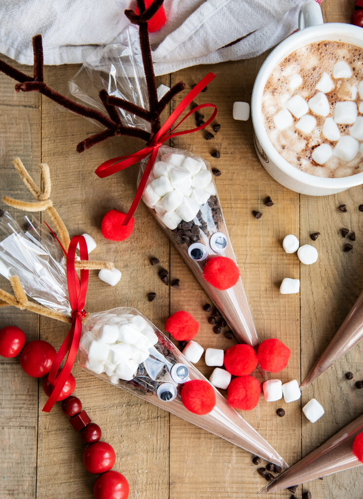 Two Hot Chocolate Cones decorated with pom poms, eyes, and brown pipe cleaners for antlers, to look like reindeer.