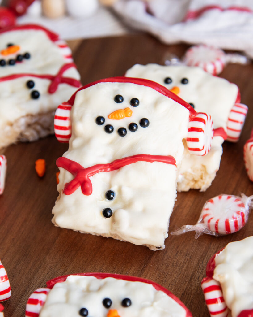 A square rice krispie treat decorated with candy and sprinkles to look like a snowman.