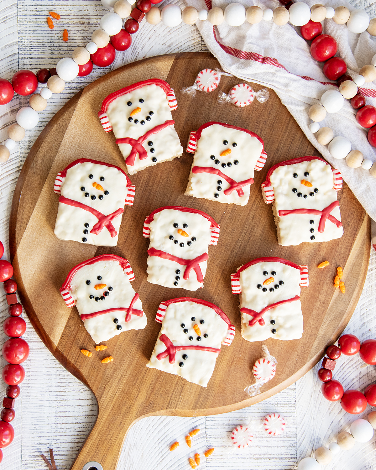 Snowman Rice Krispie Treats on a round cutting board.